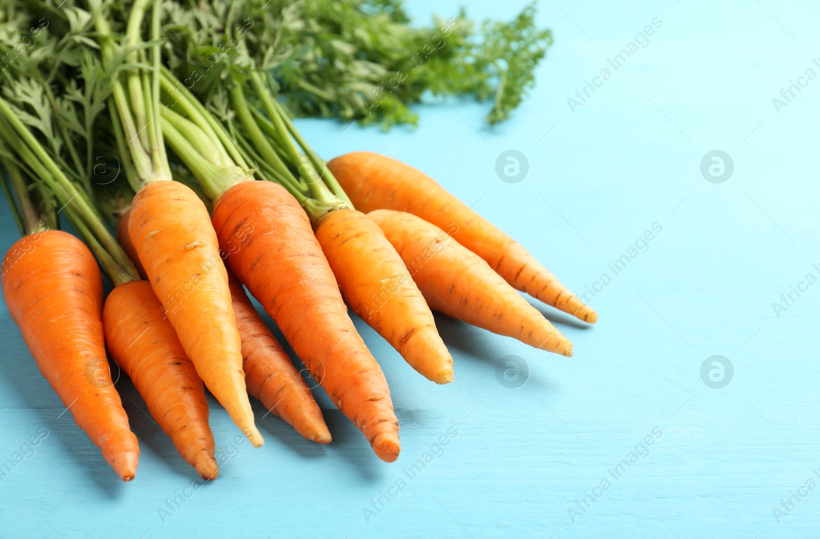 Photo of Tasty ripe juicy carrots on light blue wooden table