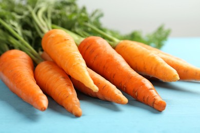 Photo of Tasty ripe juicy carrots on light blue wooden table, closeup