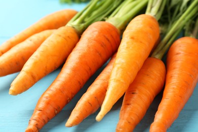 Tasty ripe juicy carrots on light blue wooden table, closeup