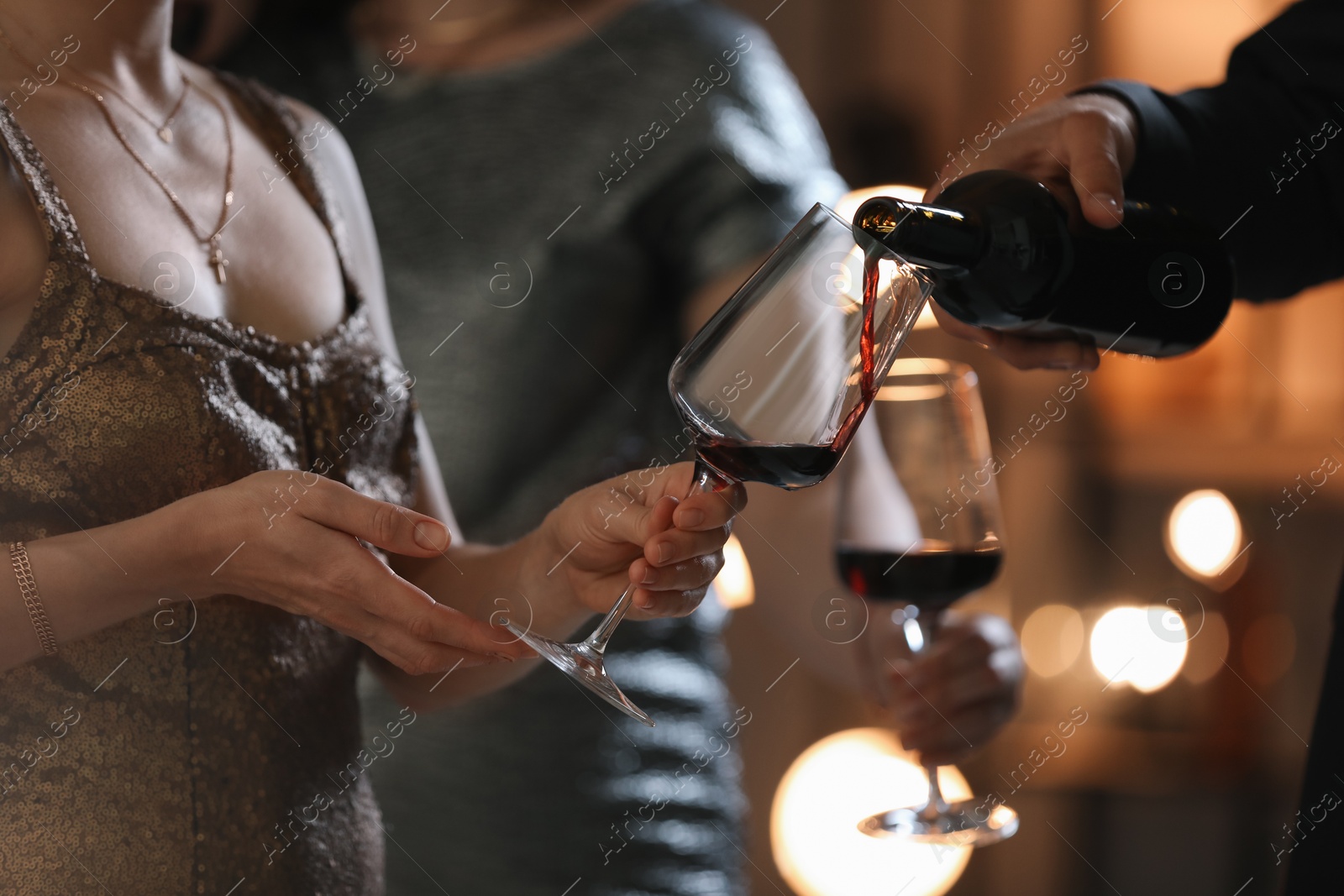 Photo of Man pouring wine into woman`s glass indoors, selective focus