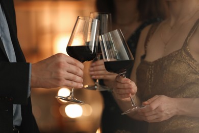 Photo of Women and man clinking glasses of tasty wine at party, closeup