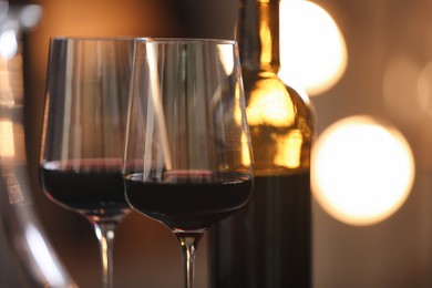 Photo of Tasty wine in glass and bottle against blurred lights, closeup