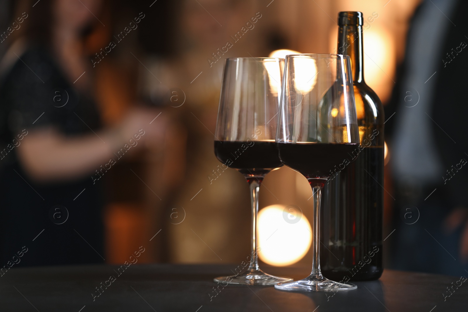 Photo of Tasty wine in glasses and bottle on black table indoors, selective focus