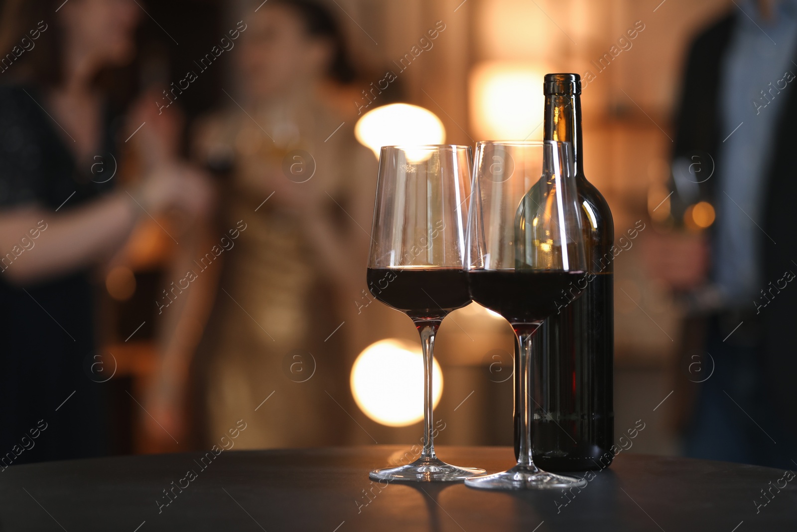 Photo of Tasty wine in glasses and bottle on black table indoors, selective focus