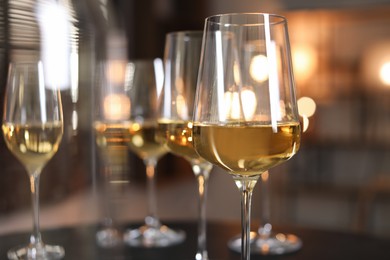 Tasty wine in glasses on table against blurred lights, closeup