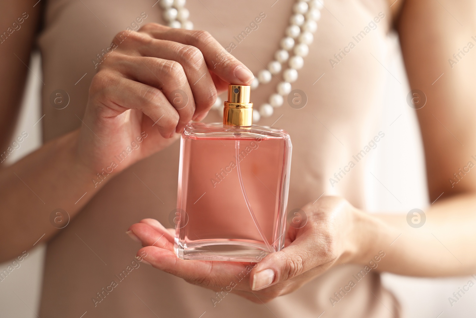 Photo of Woman with bottle of perfume on blurred background, closeup