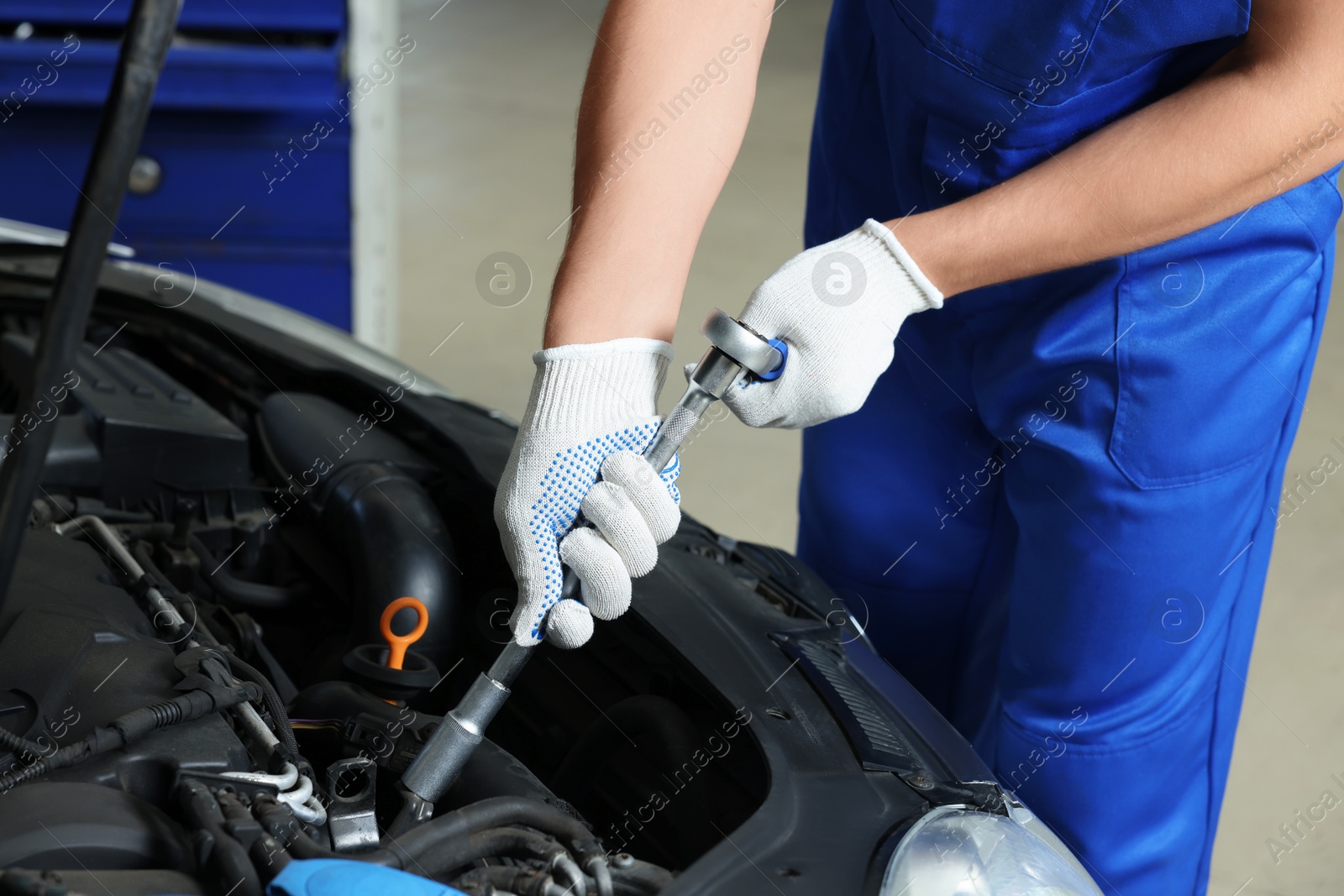 Photo of Auto mechanic fixing car at automobile repair shop, closeup