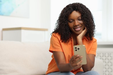 Photo of Beautiful woman using mobile phone at home, space for text