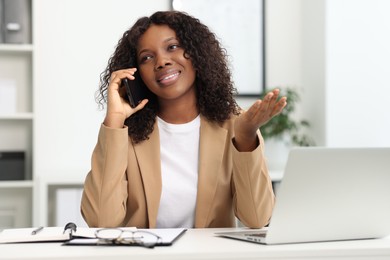 Photo of Beautiful woman talking on mobile phone in office