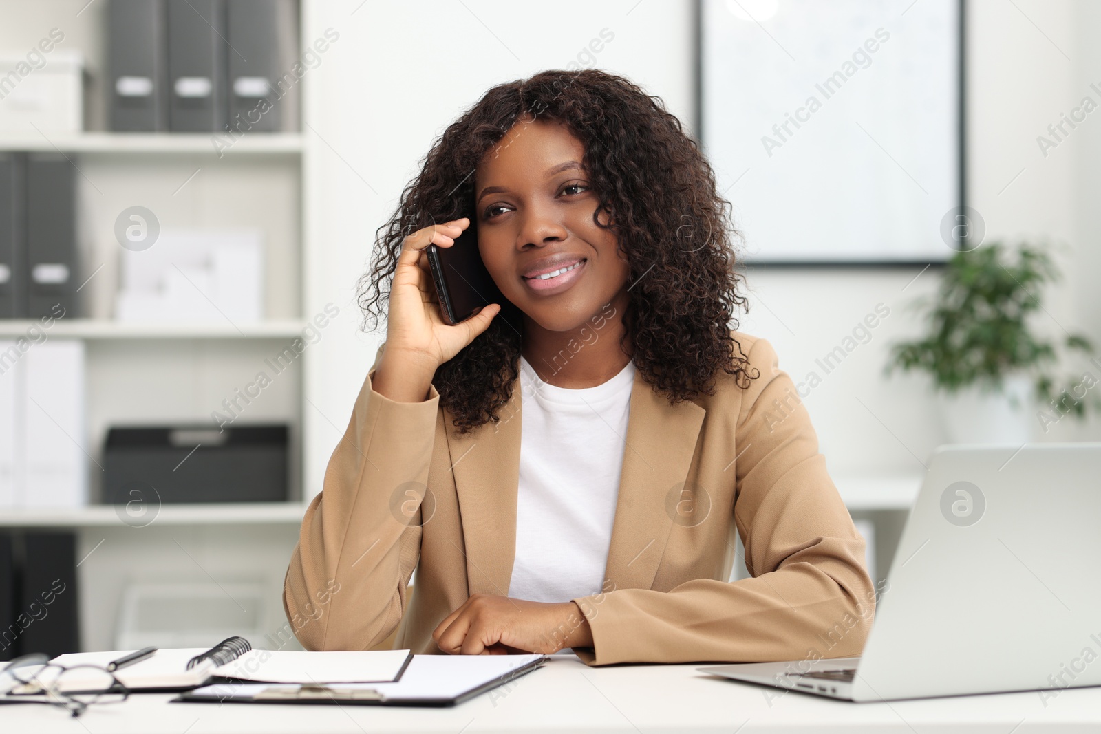 Photo of Beautiful woman talking on mobile phone in office