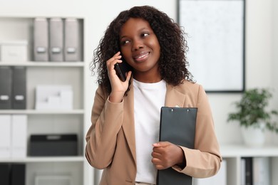 Beautiful woman talking on mobile phone in office