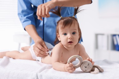 Photo of Pediatrician examining cute little girl with stethoscope in clinic, closeup. Checking baby's health