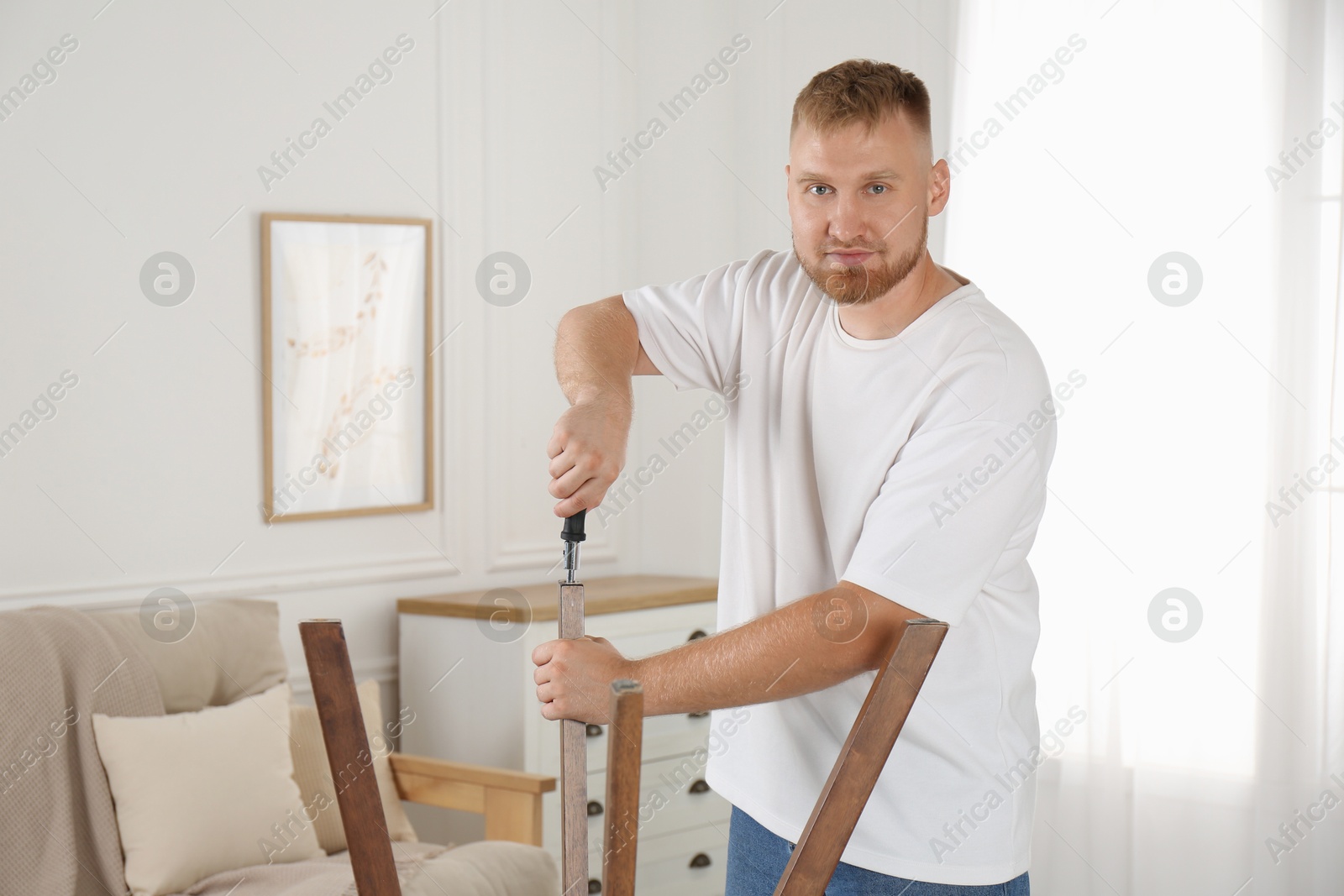 Photo of Man with screwdriver assembling furniture in room