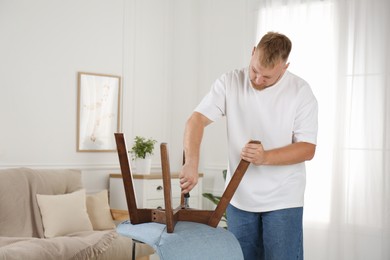 Man with screwdriver assembling chair in room