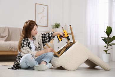 Woman with electric screwdriver assembling armchair at home