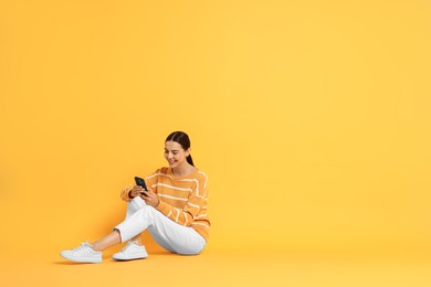 Photo of Happy woman with smartphone on yellow background. Space for text