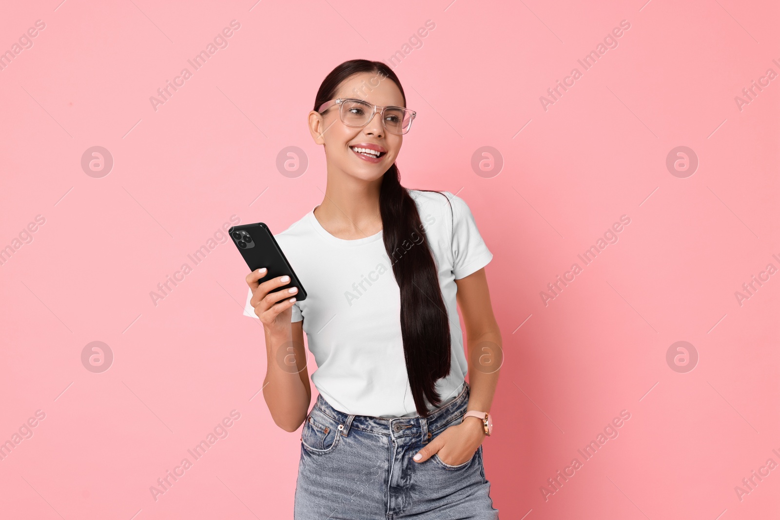 Photo of Smiling woman with smartphone on pink background