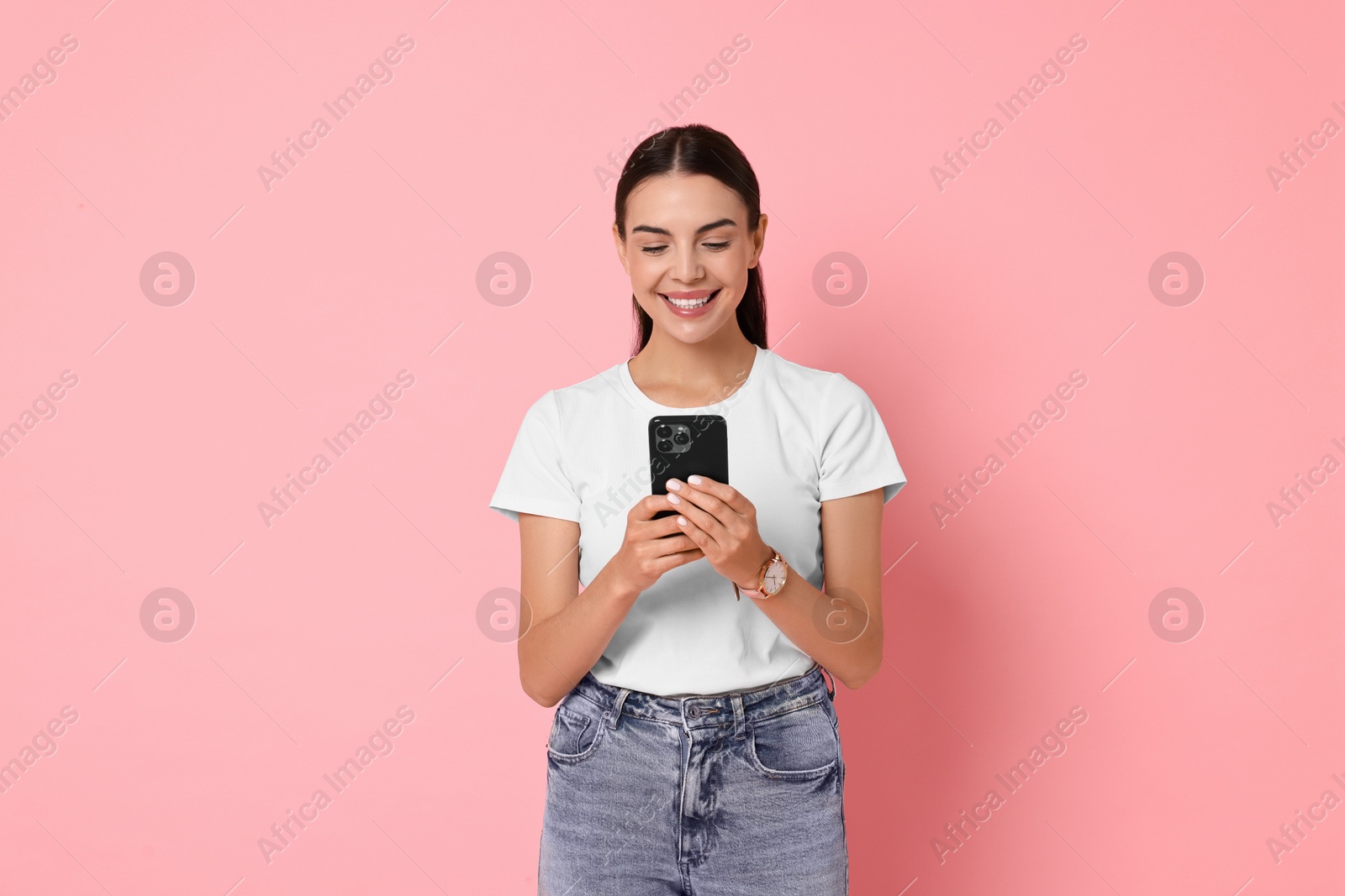 Photo of Smiling woman with smartphone on pink background