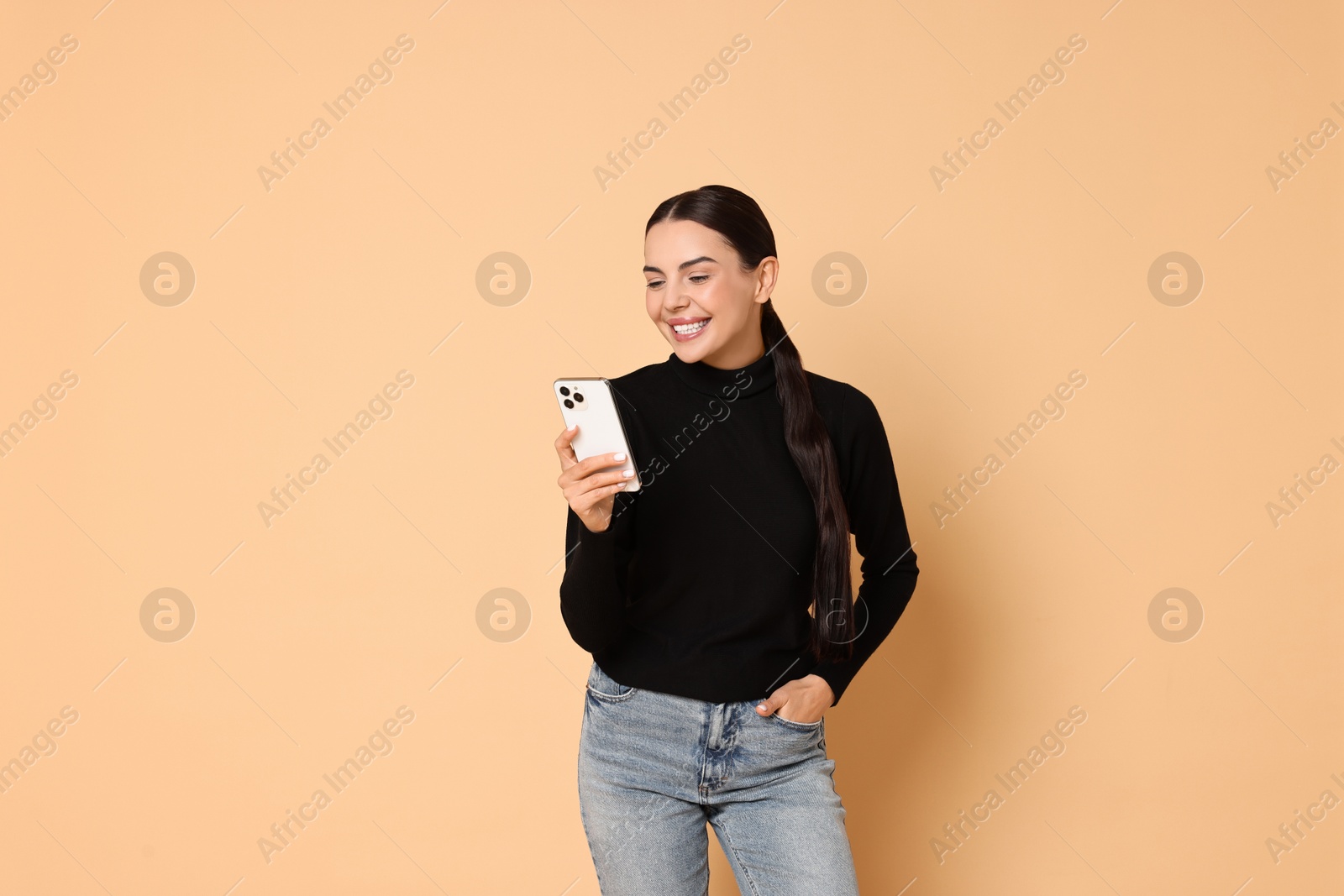 Photo of Smiling woman with smartphone on beige background