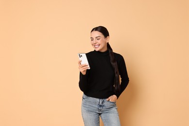 Smiling woman with smartphone on beige background