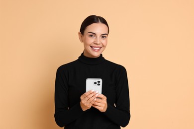 Smiling woman with smartphone on beige background