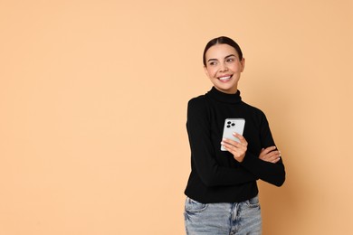 Photo of Smiling woman with smartphone on beige background. Space for text