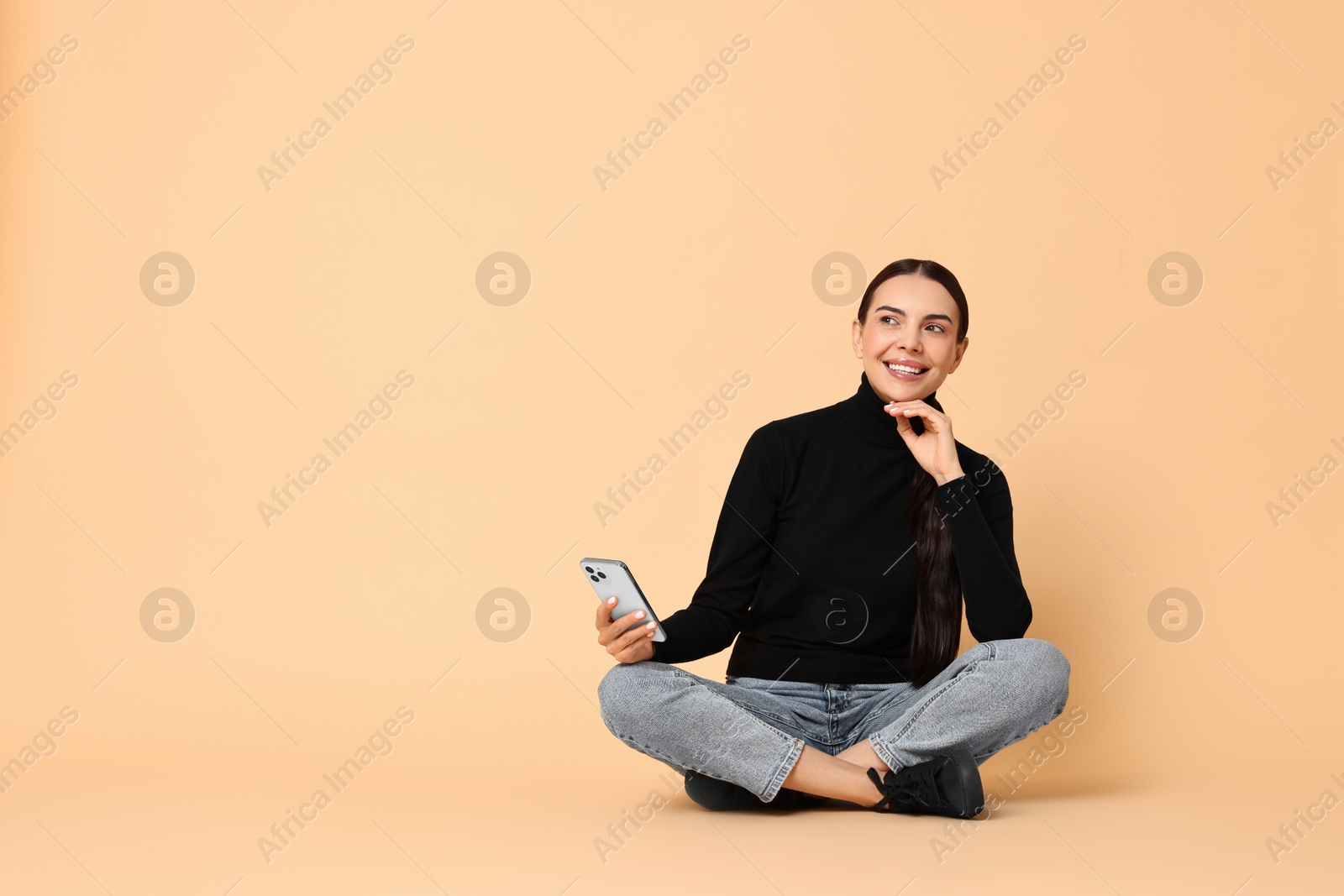 Photo of Smiling woman with smartphone on beige background. Space for text