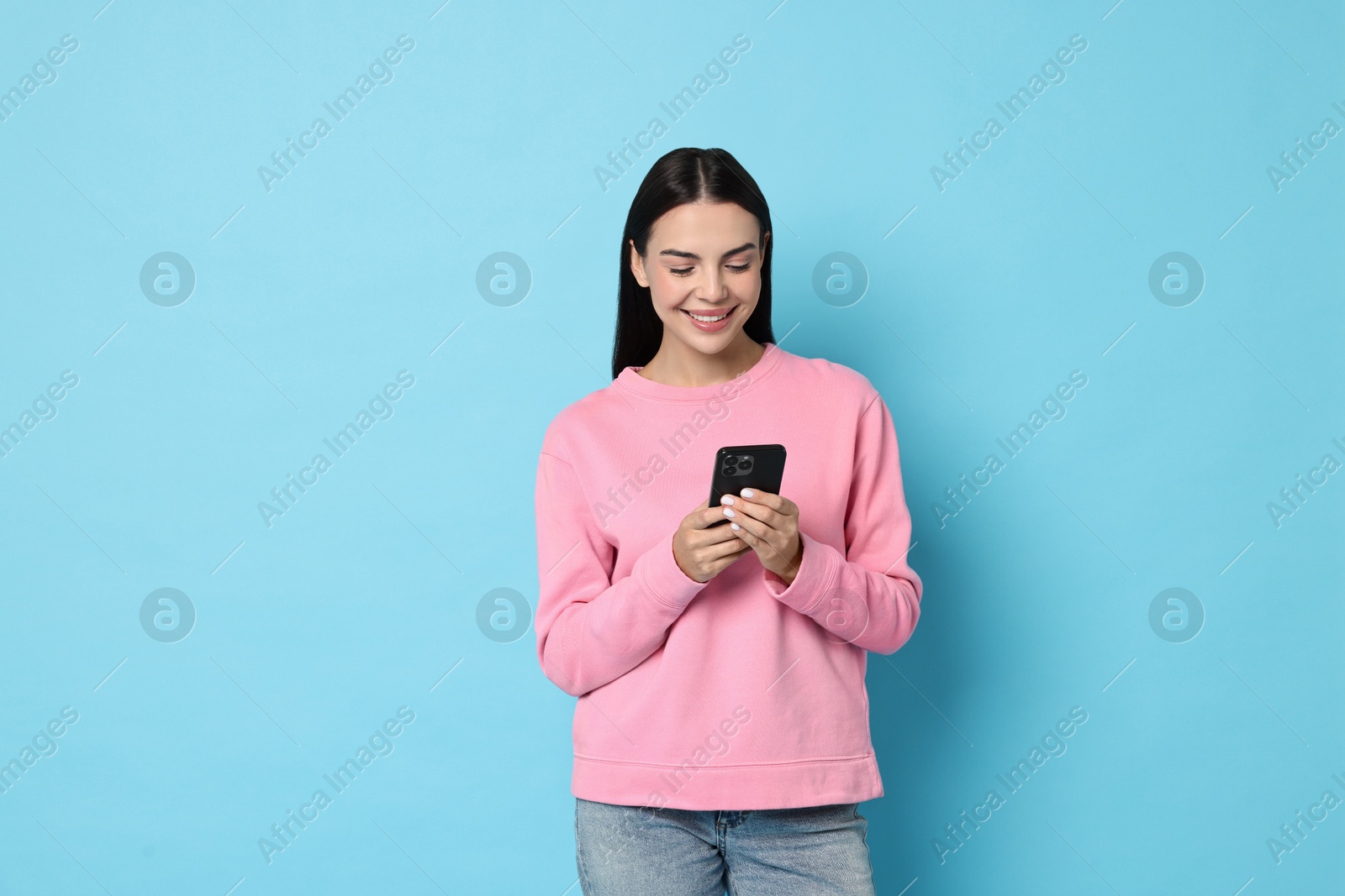 Photo of Happy woman with smartphone on light blue background