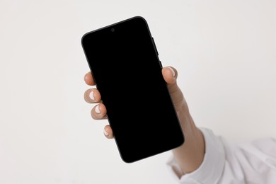 Photo of Woman holding smartphone with blank screen on white background, closeup