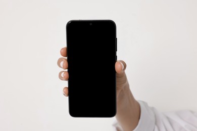 Photo of Woman holding smartphone with blank screen on white background, closeup