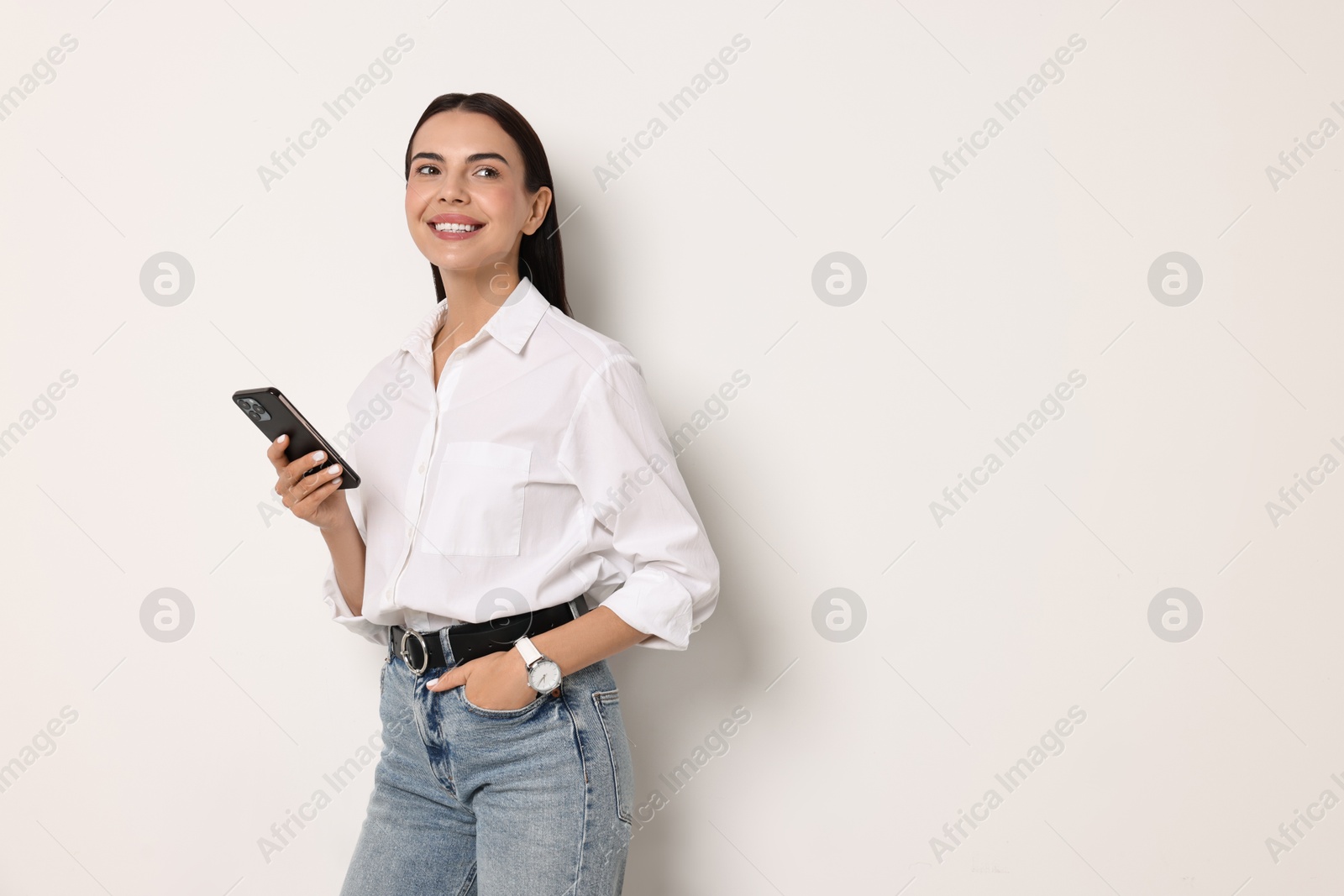 Photo of Smiling woman with smartphone on white background. Space for text