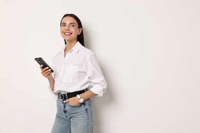 Smiling woman with smartphone on white background. Space for text