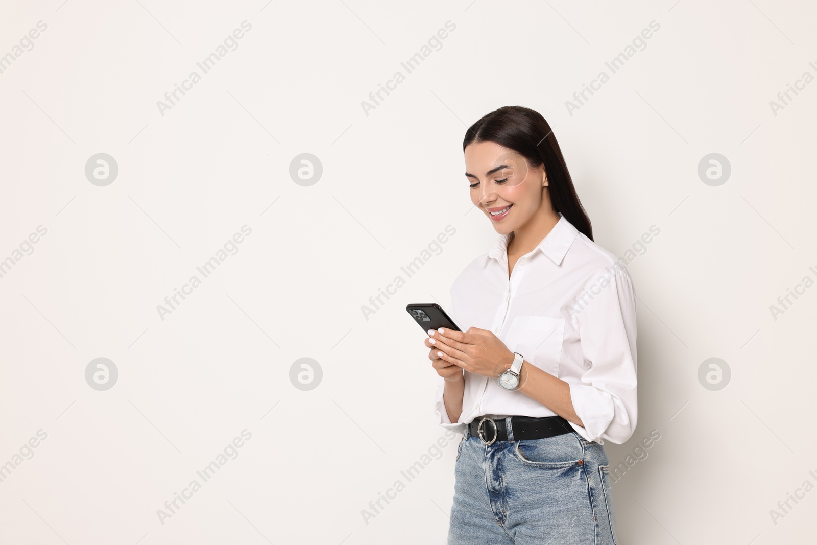 Photo of Smiling woman with smartphone on white background. Space for text