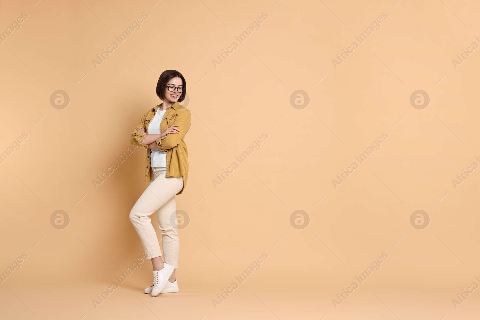 Photo of Smiling woman posing on beige background. Space for text