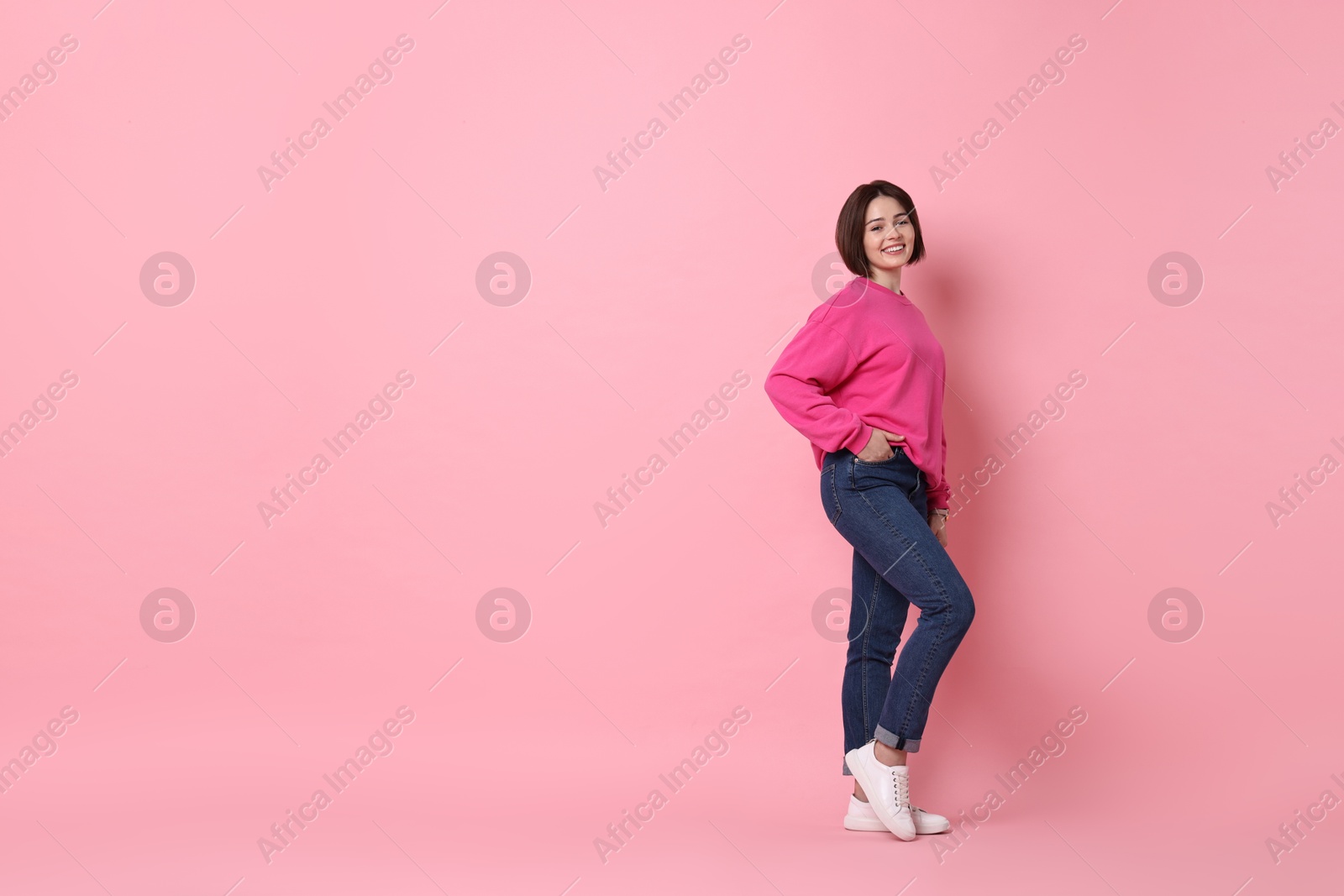 Photo of Smiling woman posing on pink background. Space for text