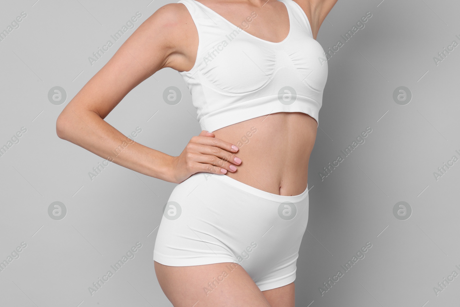 Photo of Diet and weight loss concept. Woman with slim body against light grey background, closeup