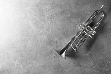 Photo of Shiny trumpet on grey textured table, top view. Space for text. Wind musical instrument