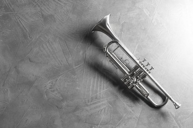 Photo of Shiny trumpet on grey textured table, top view. Space for text. Wind musical instrument