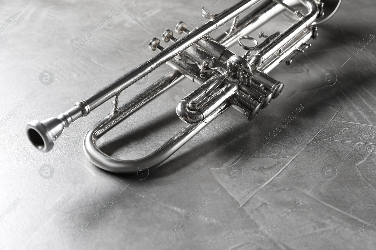 Photo of Shiny trumpet on grey textured table. Wind musical instrument