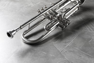 Shiny trumpet on grey textured table. Wind musical instrument