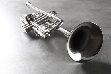 Photo of Shiny trumpet on grey textured table. Wind musical instrument