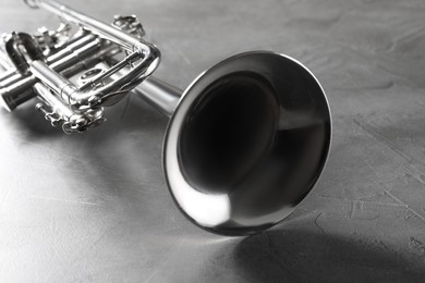 Photo of Closeup view of shiny trumpet on grey textured table. Wind musical instrument