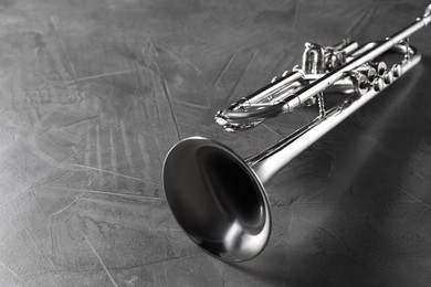 Photo of Closeup view of shiny trumpet on grey textured table. Wind musical instrument