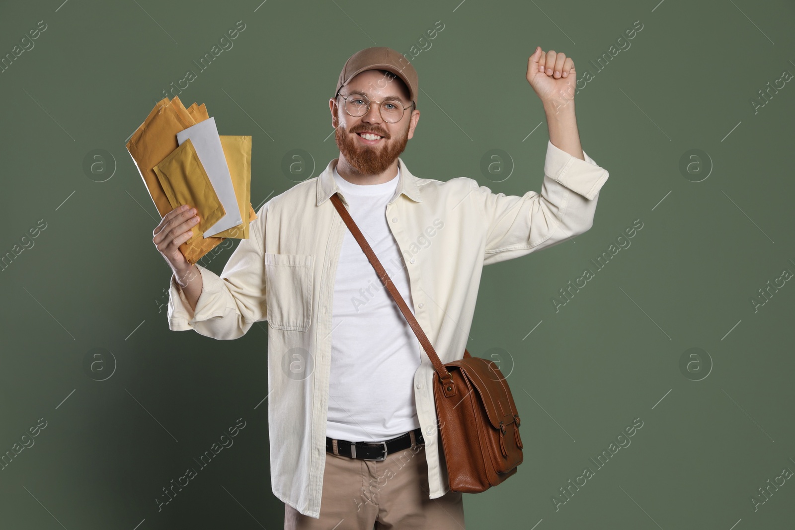 Photo of Happy young postman with brown bag delivering letters on olive background