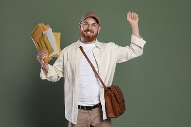 Happy young postman with brown bag delivering letters on olive background