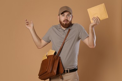 Photo of Emotional young postman with leather bag delivering letters on brown background