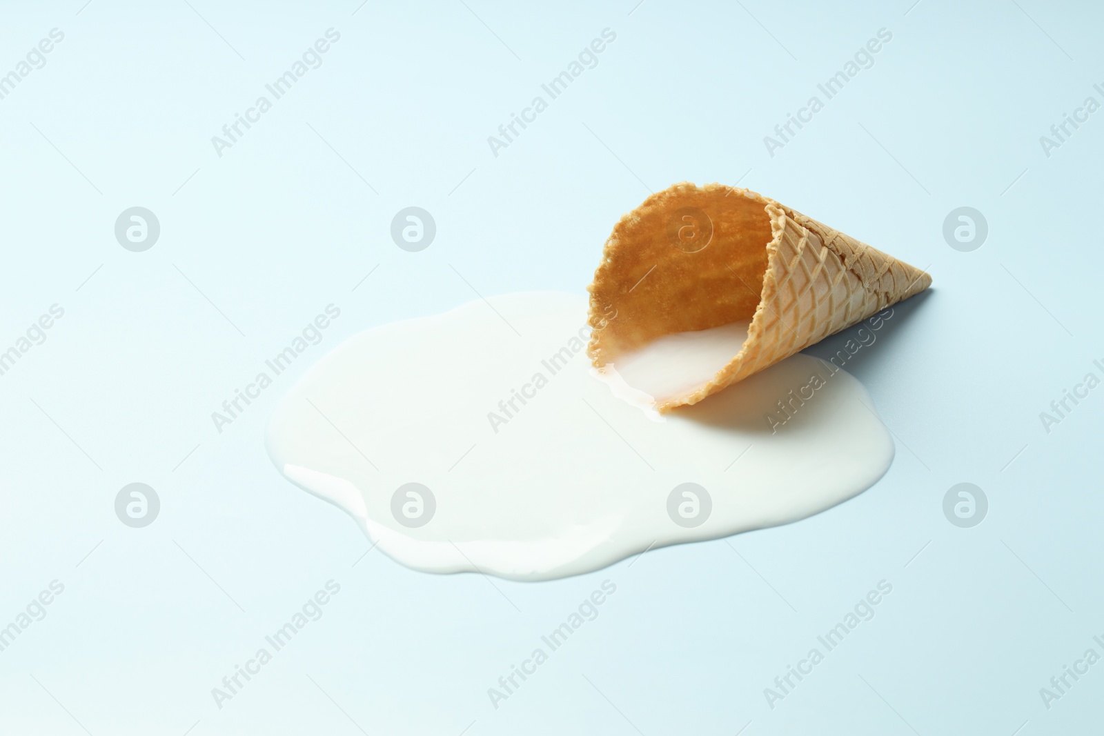 Photo of Melted ice cream and wafer cone on light background