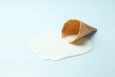 Photo of Melted ice cream and wafer cone on light background