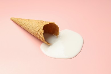 Photo of Melted ice cream and wafer cone on light pink background