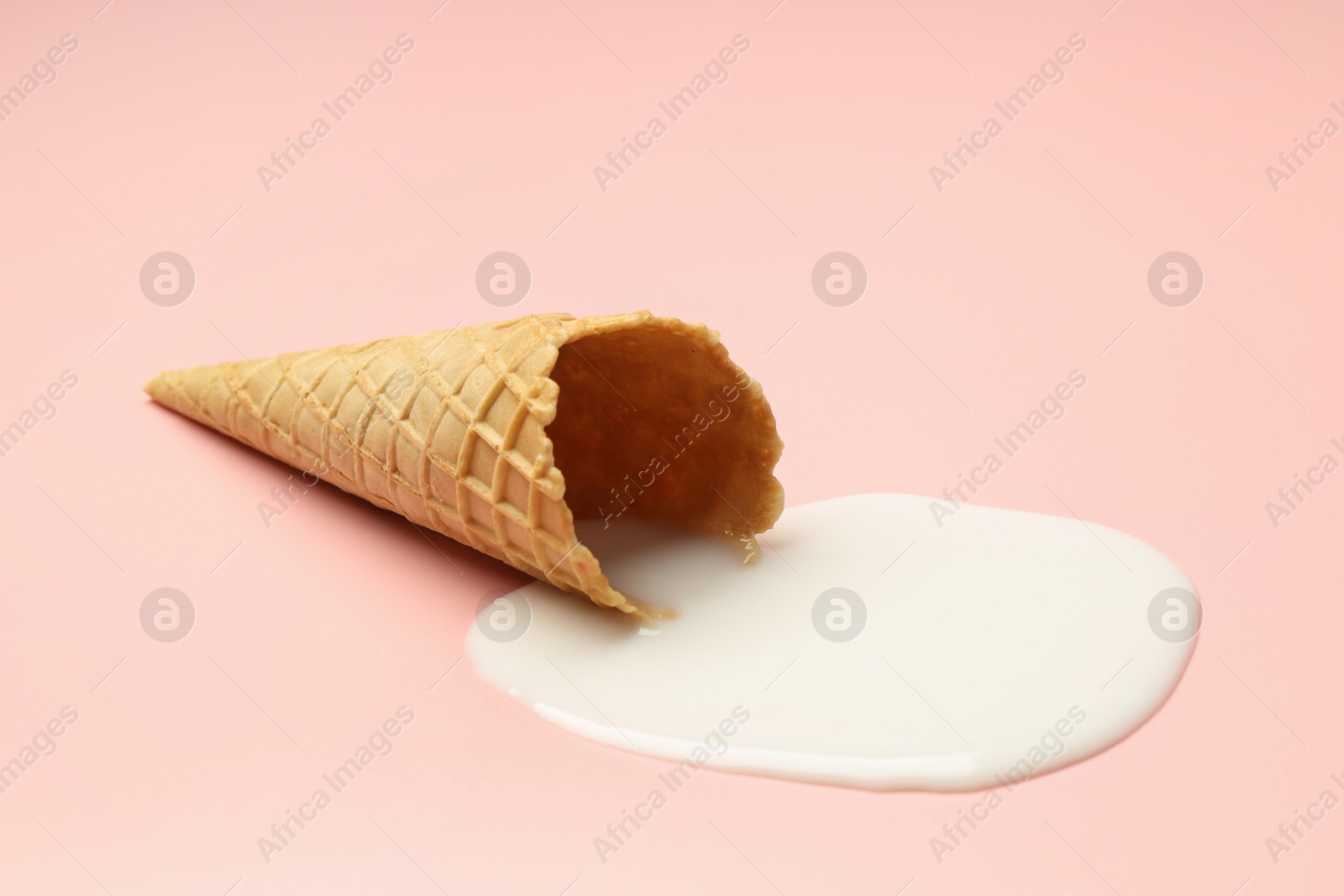 Photo of Melted ice cream and wafer cone on light pink background